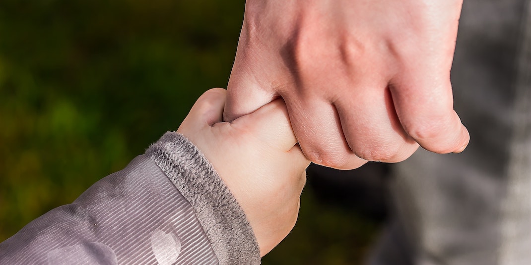 Baby holding adult's finger