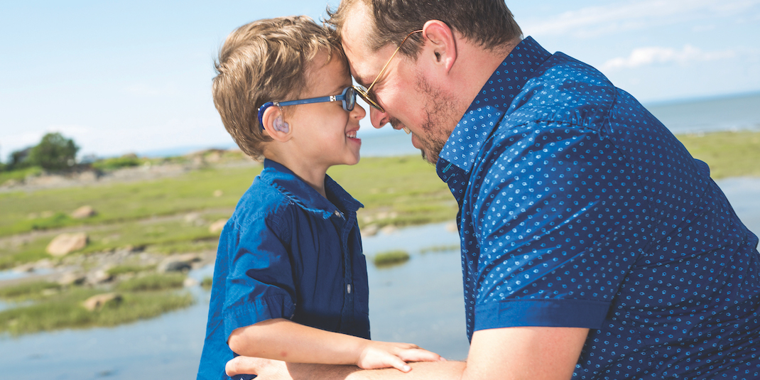 Boy with hearing aides alongside father