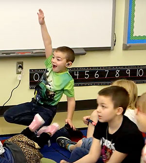 Boy energetically raising his hand in class